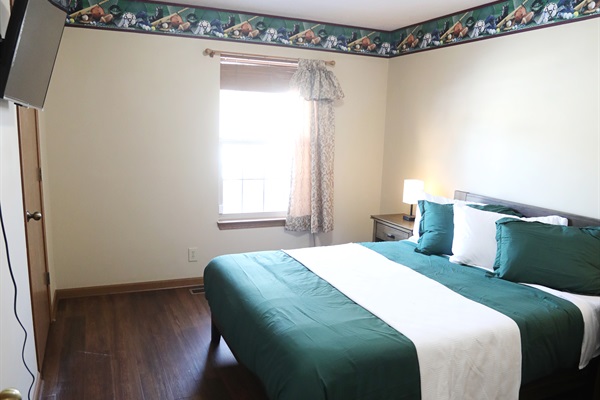 SE bedroom showing showing queen size bed, Roku TV, dresser, nightstands with touch lamps, and alarm clock