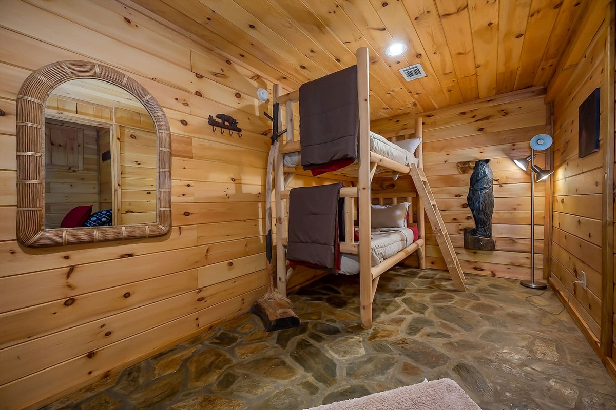 Lower-level open bedroom/game room. Bedroom has bunk beds, an additional twin bed and a queen futon sleeper. Door opens to large back yard and deck with swing and seating.