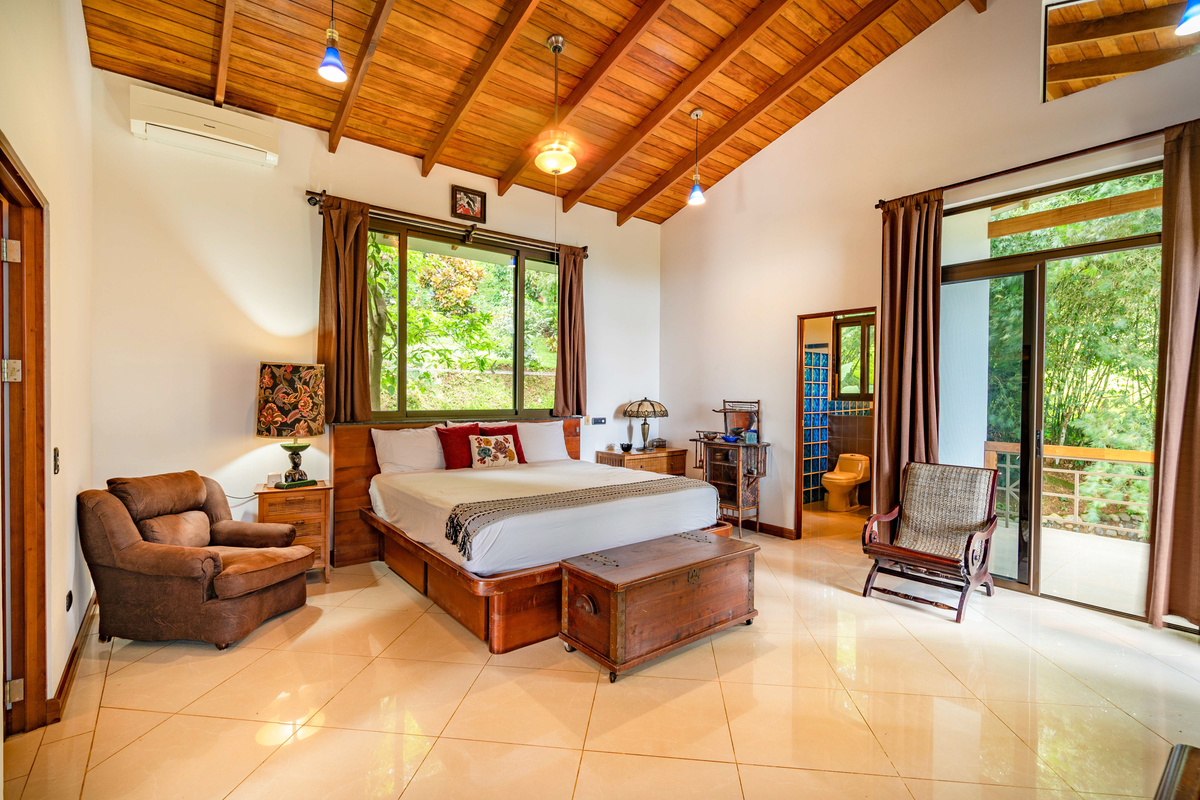 King bedroom suite with warm tropical hardwoods, ensuite bathroom, and lush garden views