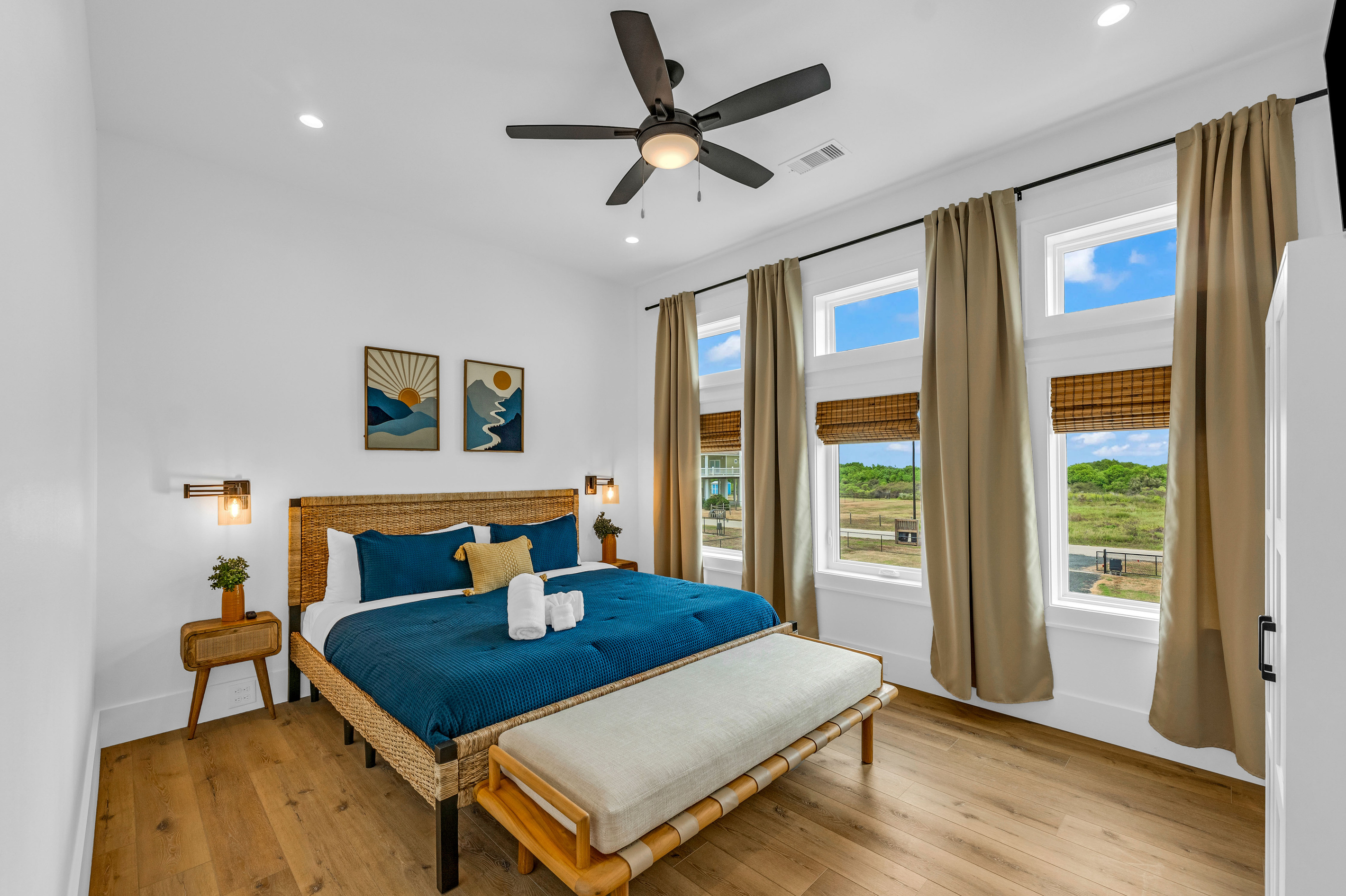 Cair Paravel: Navy blue bedding and sunrise-toned art play against warm wood floors and a wall of windows. 