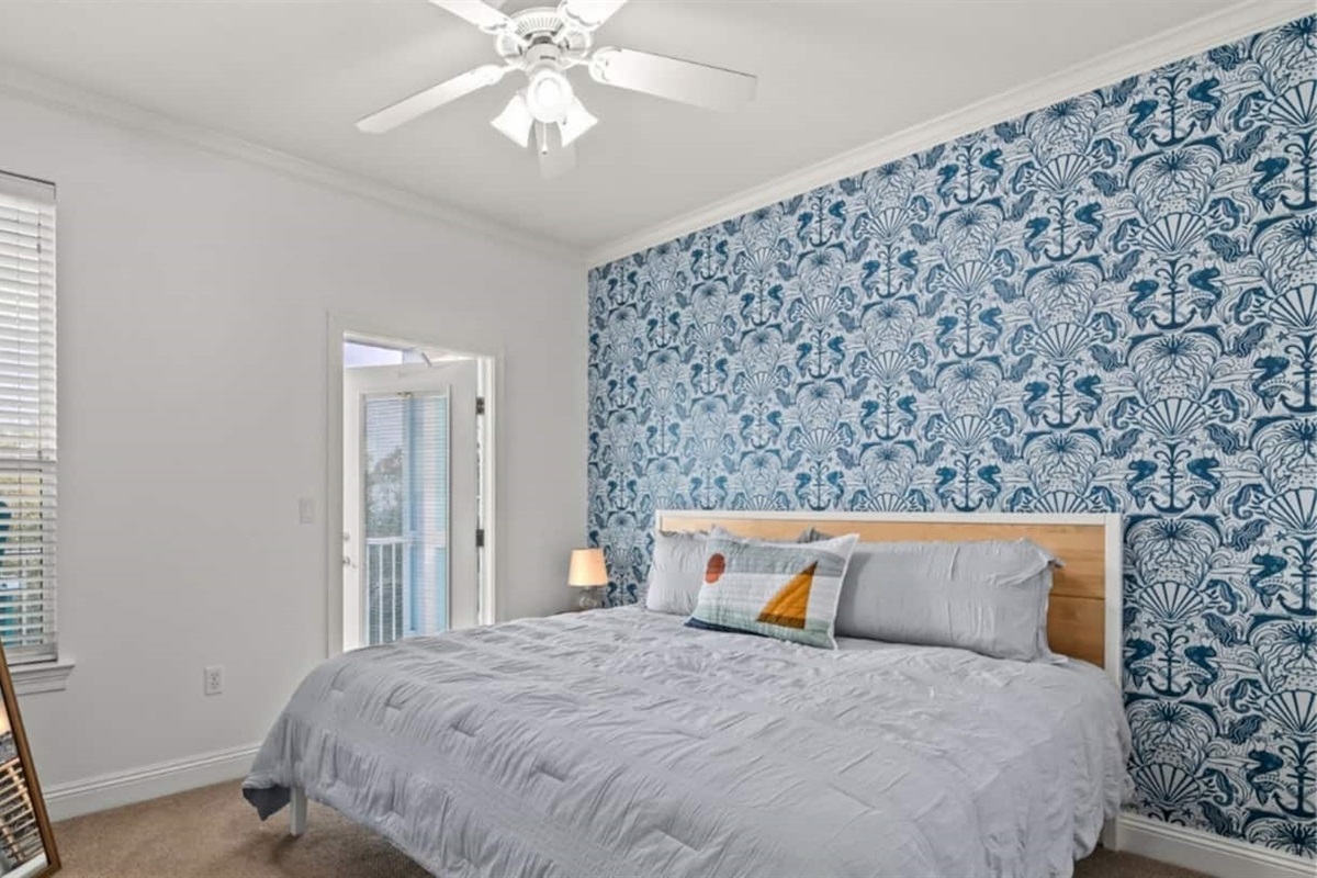 A king bed and whimsical seahorse wallpaper that says you're at the beach.