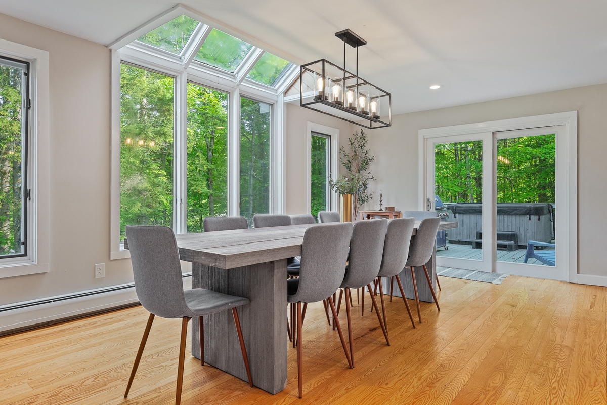 Dining room seating 10 beneath a wall of windows with direct deck access