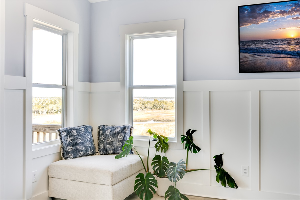 A cozy reading nook framed by tall windows, perfect for quiet moments and natural light!