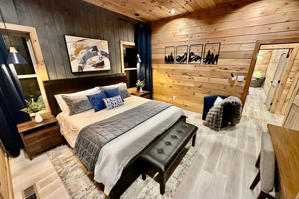 A cozy mountain bedroom with warm wood walls, plush bedding, and calm lighting. Designed for rest and reset, this inviting space is perfect for slow evenings and peaceful mornings after days spent exploring.