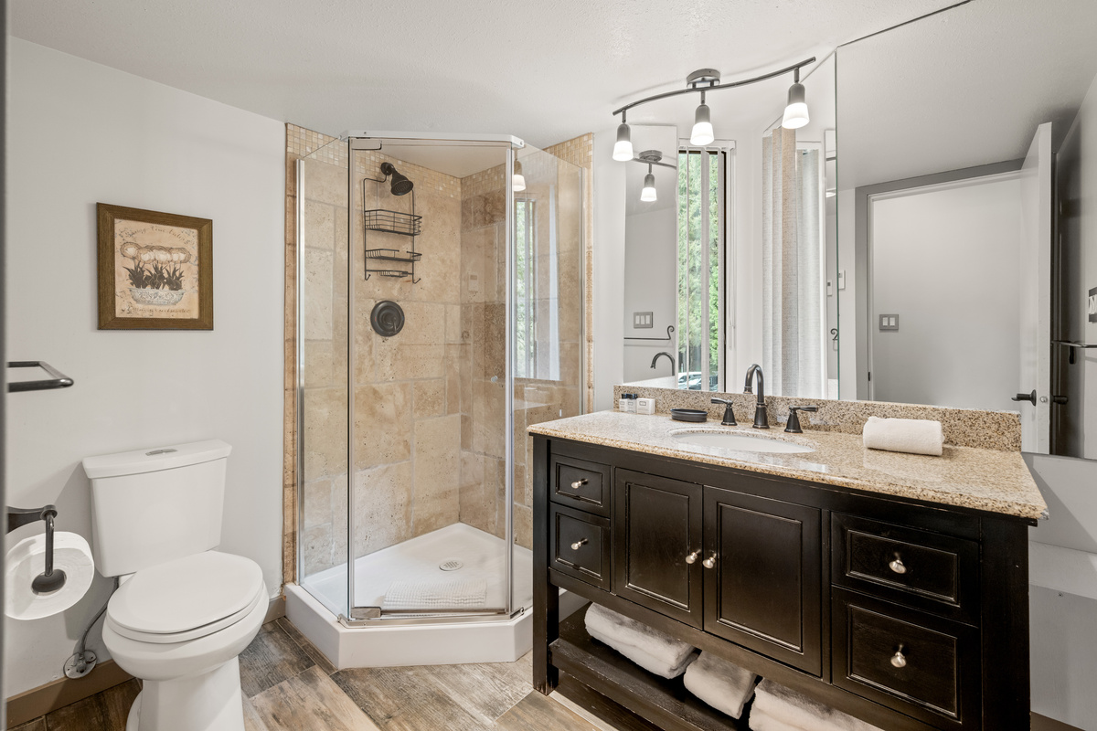 Main-floor 3-piece bathroom with a glass walk-in shower and dark vanity, one of 2 full bathrooms.