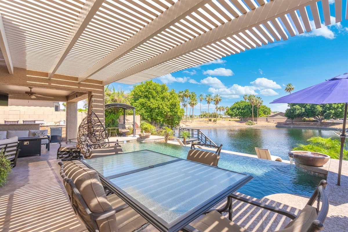 The pergola patio stretches out toward the pool and lake, offering the perfect blend of shade, breeze, and views — dine, lounge, or simply sit back and take it all in.