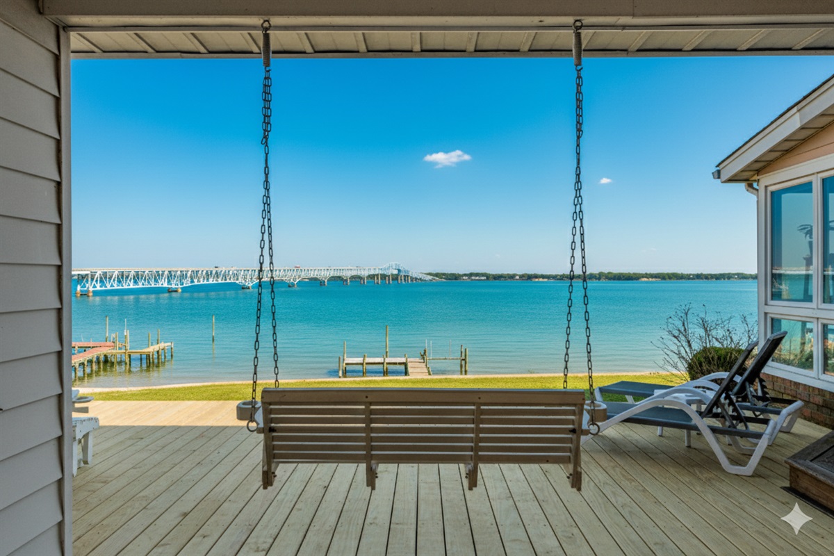 Porch Paradise: Swing into serenity with breathtaking views of the sparkling water and bridge!