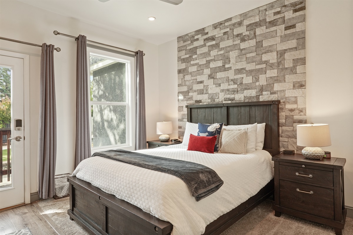 The main bedroom has a queen-sized bed, smart TV, walk-in closet, and direct access to the backyard.