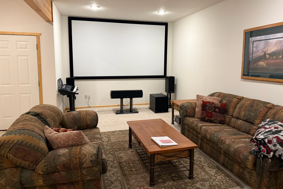 Entertainment center downstairs with large projector screen and sitting area
