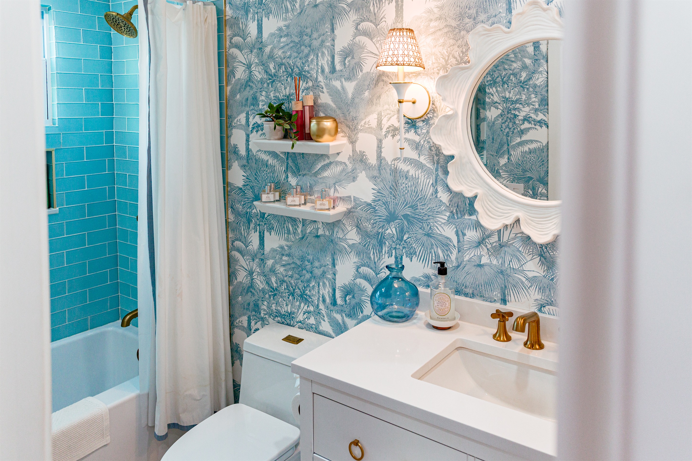 The cottage bathroom exudes palms and ocean in shades of blue and green.