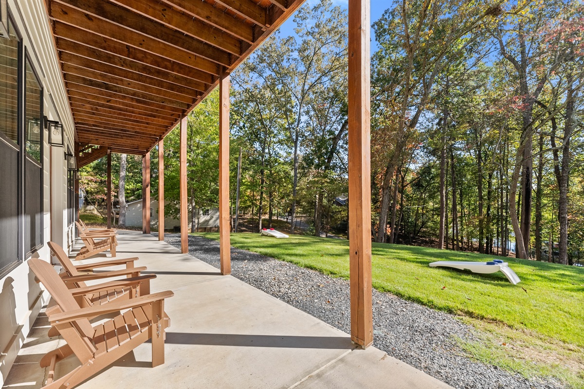 Covered patio below the deck with adirondack chairs and lake views.