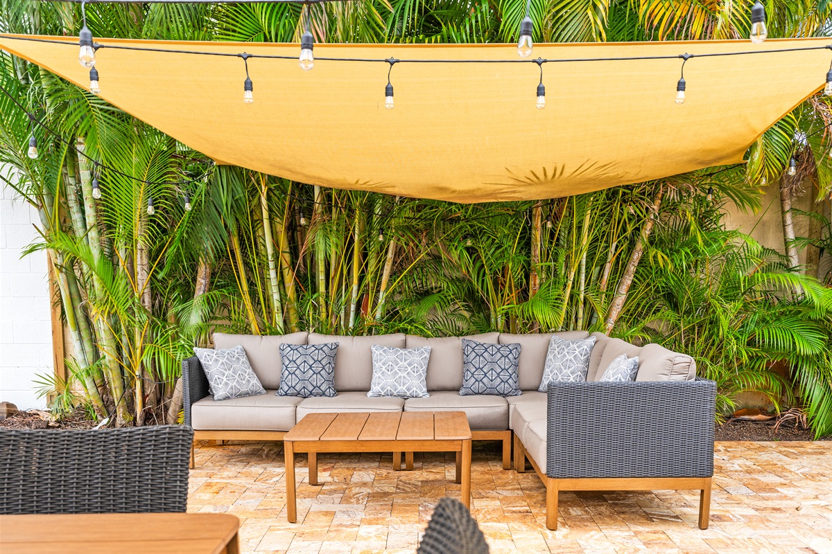 Tropical greenery, cozy cushions, and twinkling lights set the scene for laid-back luxury.