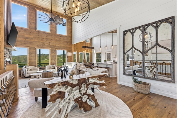 Stunning open living space with soaring ceilings, a dramatic live-edge cedar root table, and a massive mirror reflecting the views. A wall of windows showcase beautiful mountain and pasture scenery bringing the outside in!