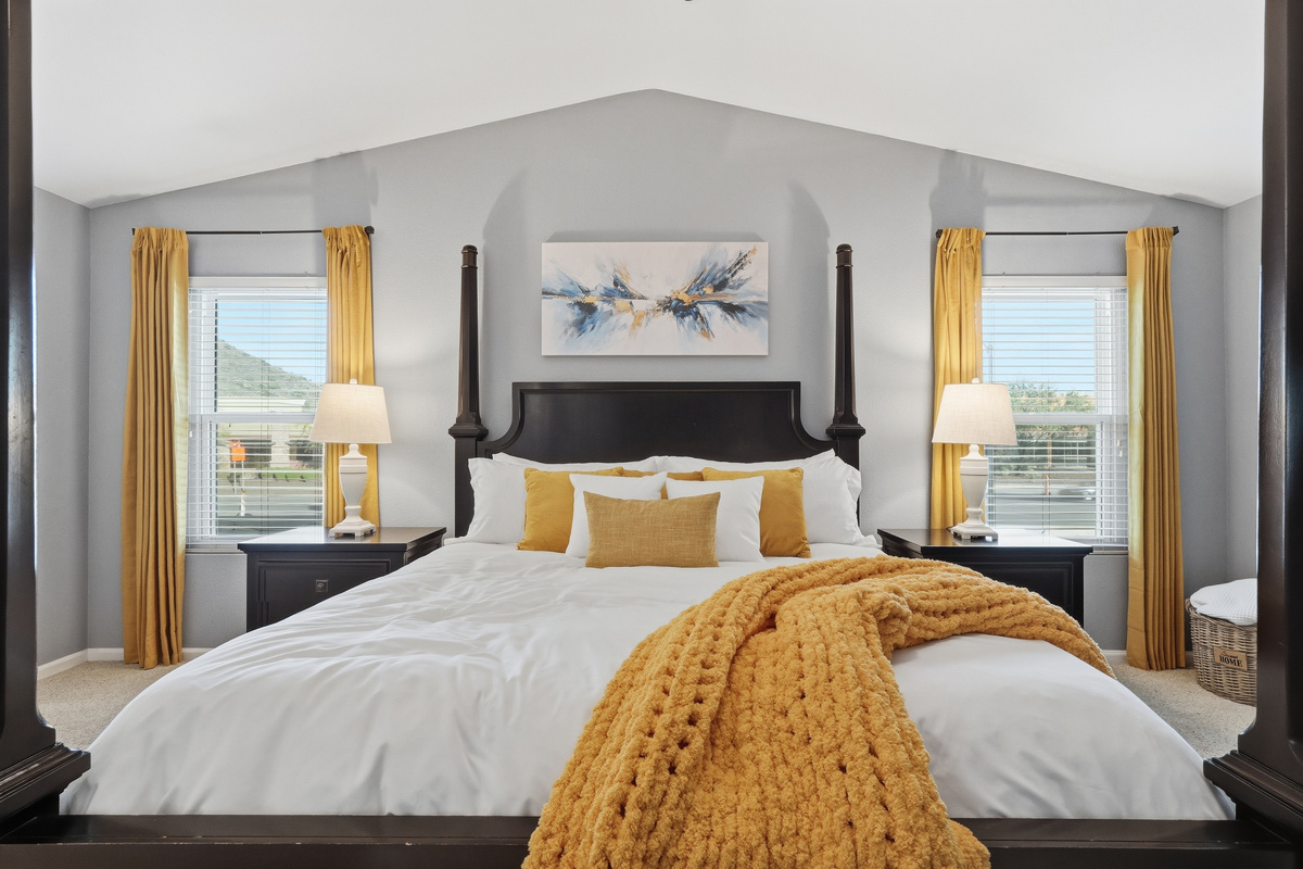 Primary bedroom with king bed, vaulted ceiling, bedside lighting, and mountain views for a restful stay.