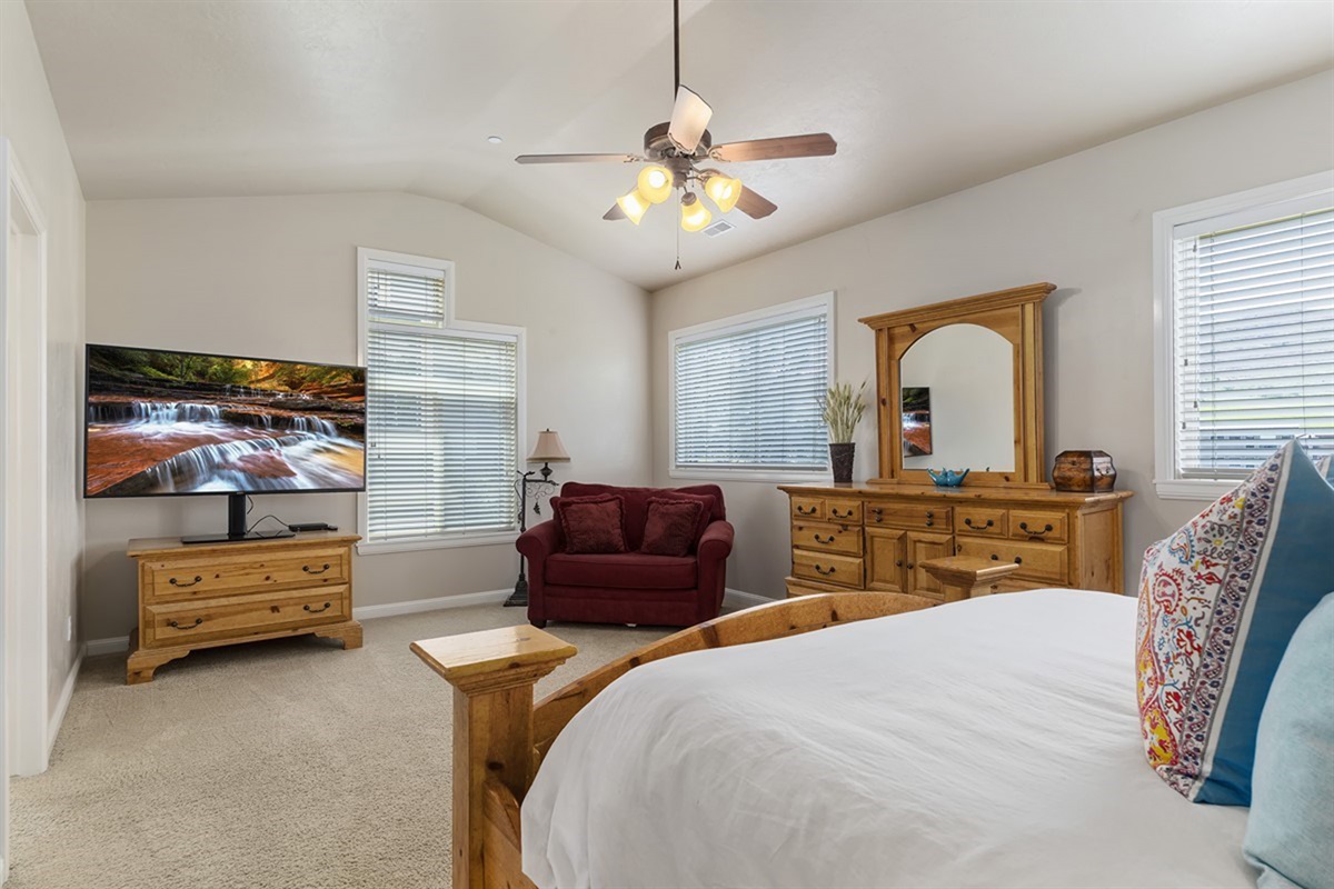 Spacious primary bedroom with California king bed, cozy seating, and plenty of natural light.