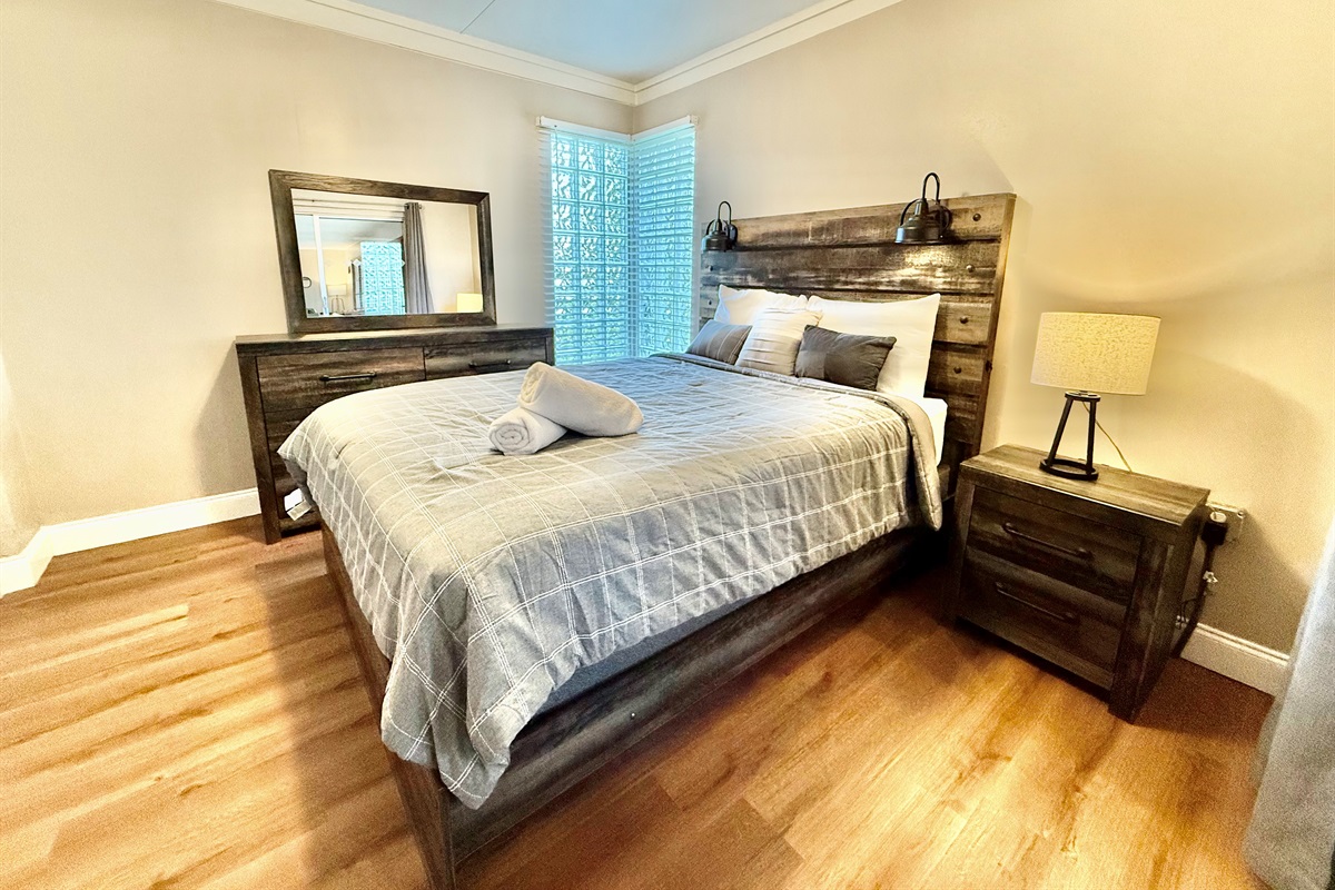 This inviting bedroom offers the perfect blend of style and comfort with its modern wooden bedframe, mirrored closet, and calming decor.