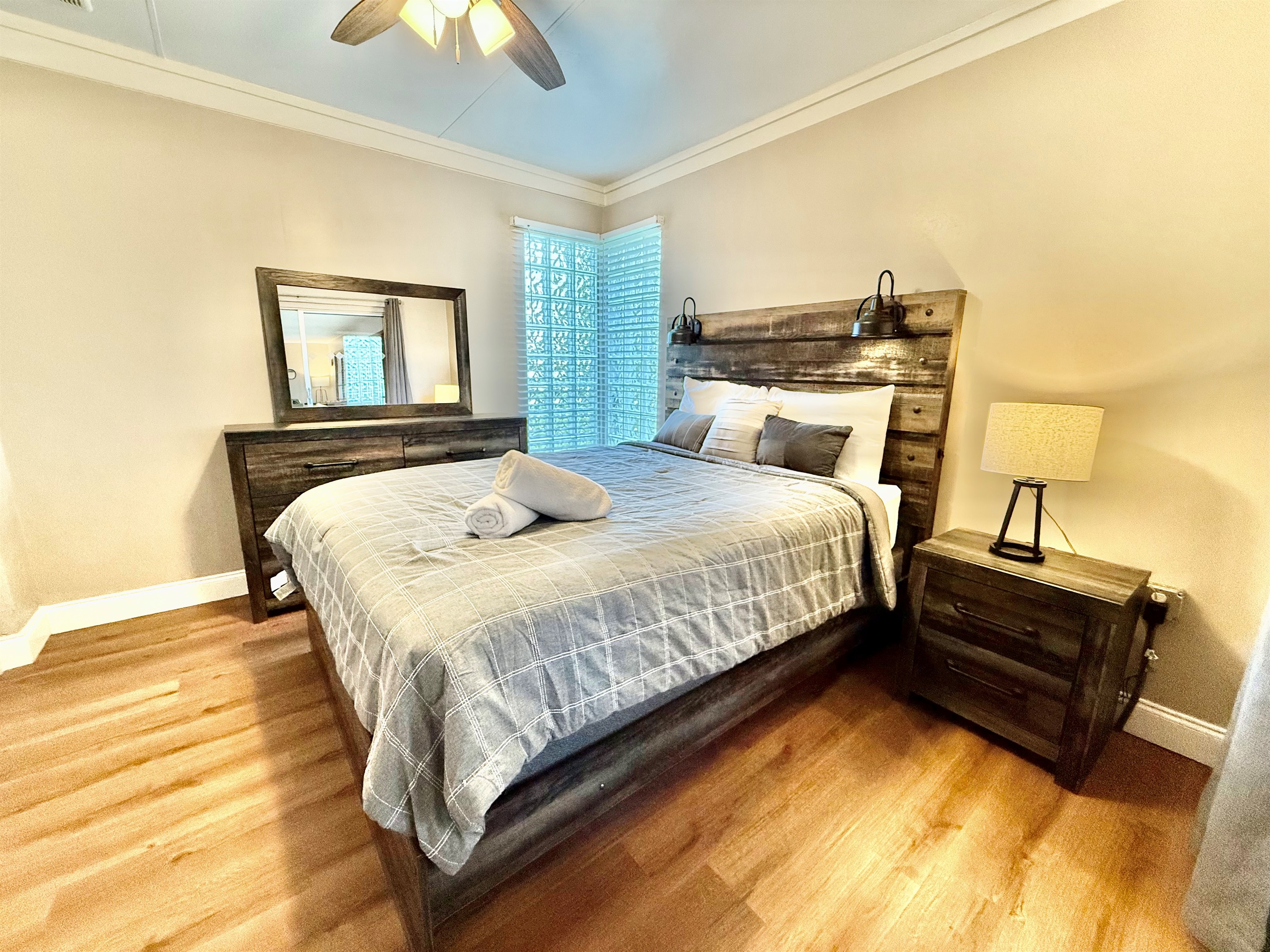 This inviting bedroom offers the perfect blend of style and comfort with its modern wooden bedframe, mirrored closet, and calming decor.