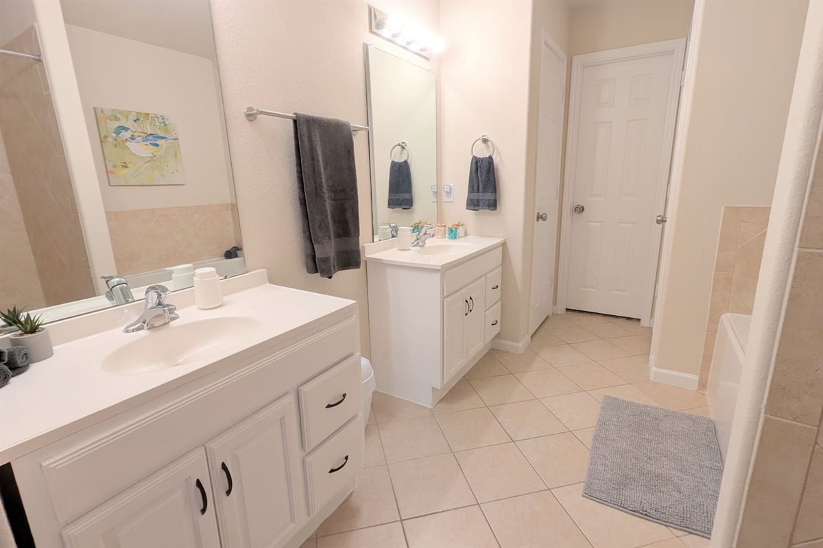 Large primary en suite bathroom has double vanities, shower, toilet closet, and jetted tub. 