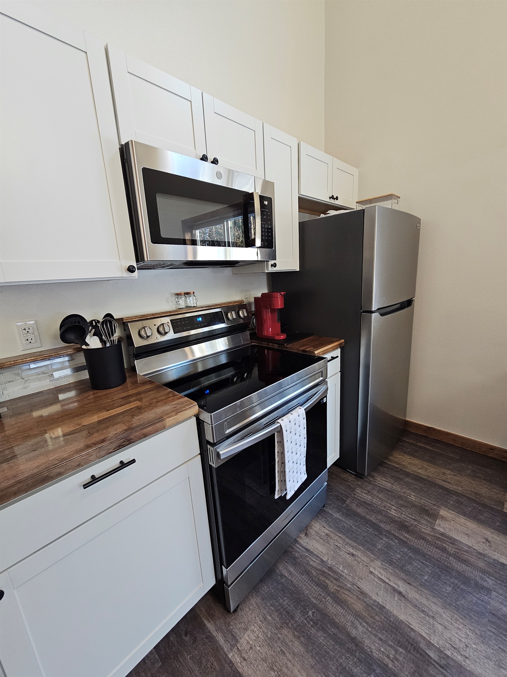 Kitchen includes an electric range, refrigerator, and Keurig.