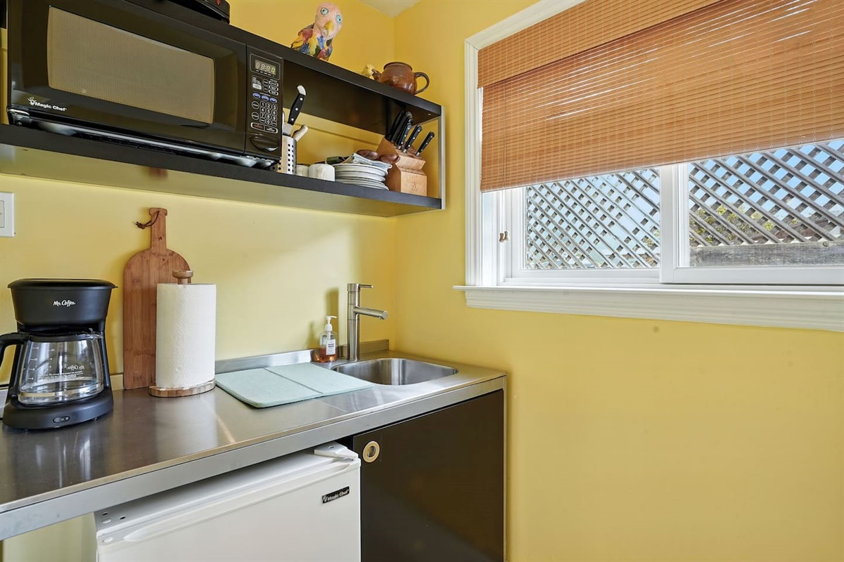 - Compact kitchenette with stainless steel sink, mini fridge, and microwave  
- Open shelving stocked with dishes, mugs, and cooking essentials for convenience  
- Ideal for preparing light meals or morning coffee before heading out  