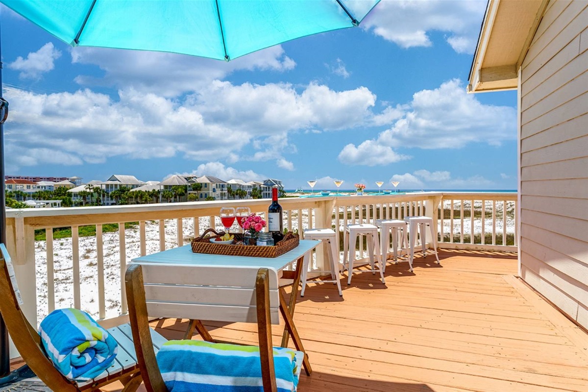 This is why you book The Perch. The wraparound deck has a full dining setup, built-in bar seating, and views of the Gulf and Destin jetties.