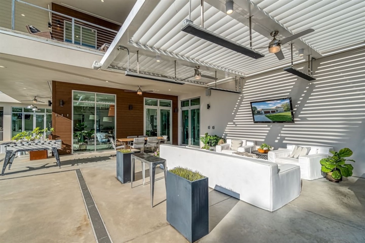 Patio with retractable awning and overhead heaters and fans with couches and tv