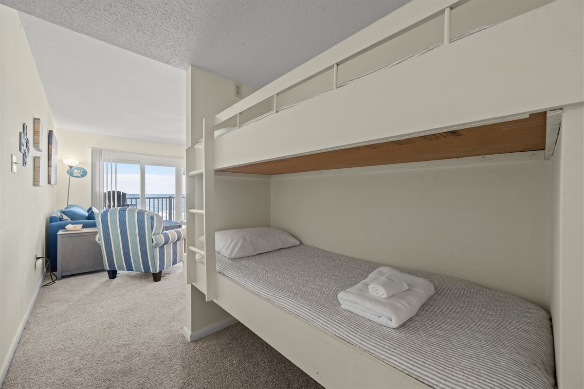 Built-in bunk nook offers a cozy sleeping setup with easy access to the living area and a peek toward the ocean-view balcony