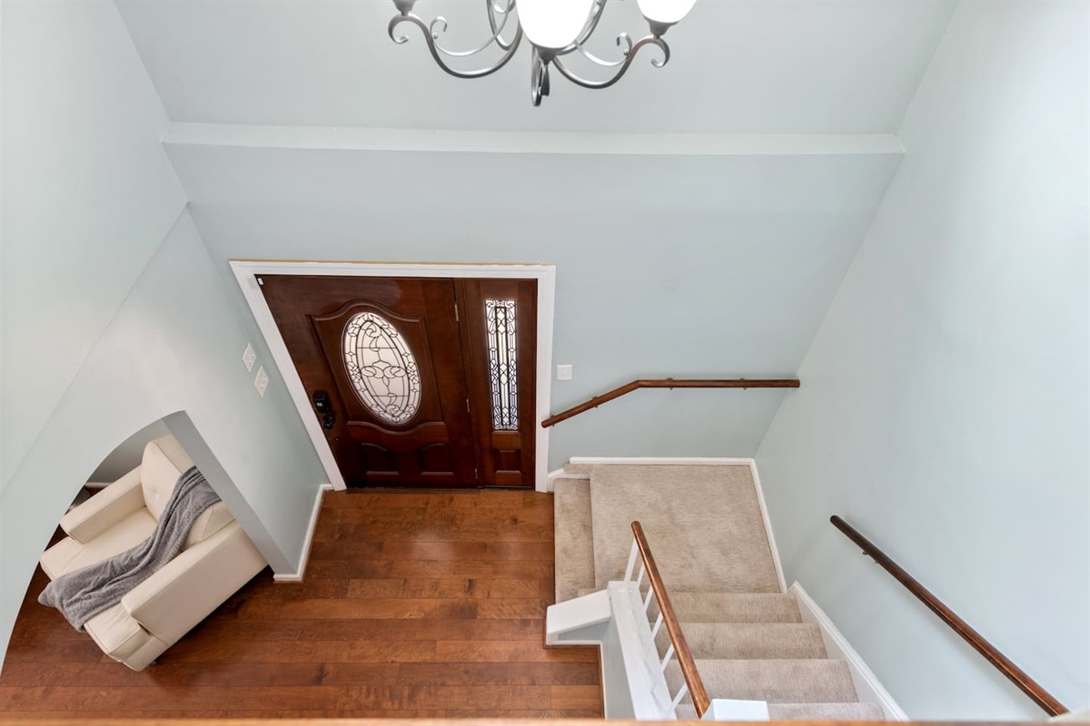 Bright and open foyer with elegant chandelier and stairway landing — a warm welcome that feels like home. 