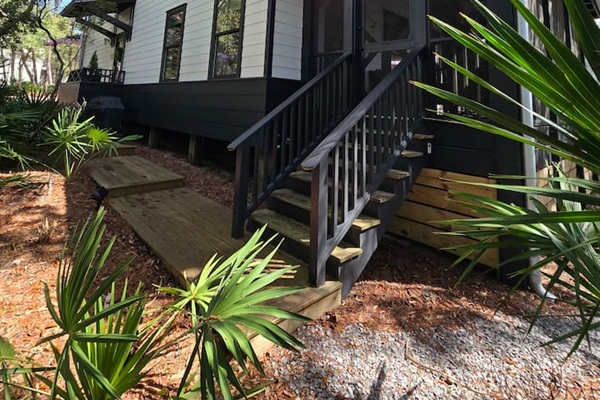 Step up to the inviting screened porch, framed by tall pines and natural landscaping. A charming entryway that blends modern cottage style with the peaceful beauty of the outdoors. ✨