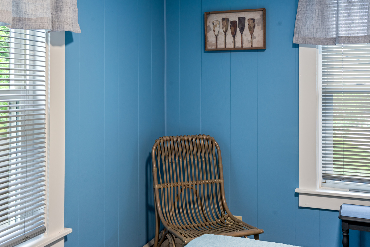 Pull up a seat in your private bedroom corner and watch the morning light stream through the blinds. Framed by rich maritime blue walls and rustic wood accents, this cozy seating spot gives you a quiet moment to yourself before the group wakes up.