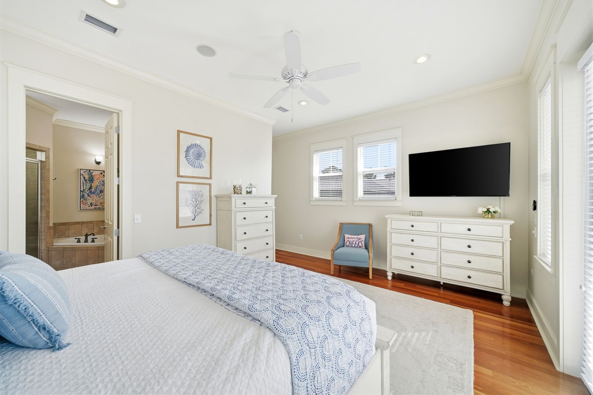 Modern comfort meets coastal charm in the main level master, complete with a flat-screen TV and private ensuite access.