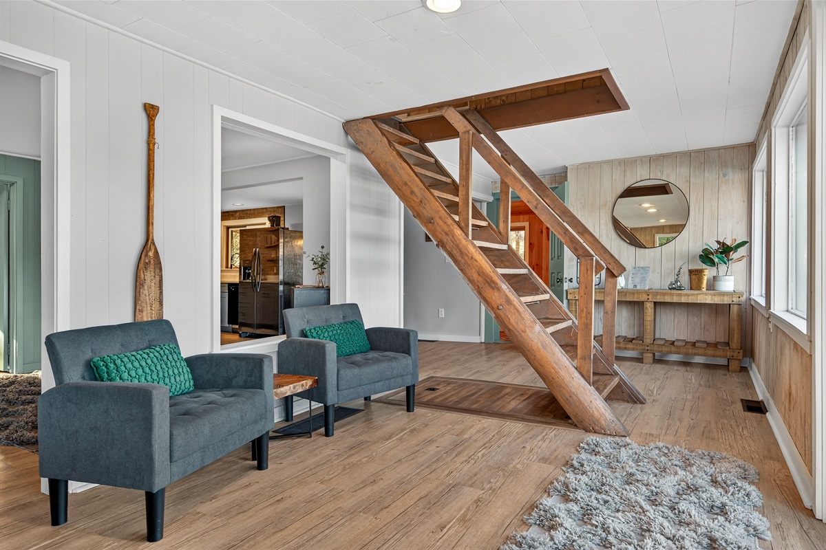Bright living room featuring a cozy seating area and the main staircase leading to the upper level.