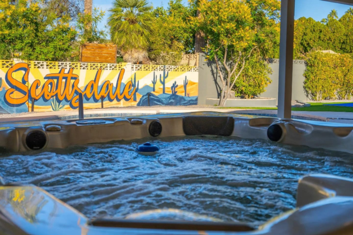 Bubbles rise in the hot tub while the hand-painted Scottsdale mural glows just beyond, a small detail that makes this backyard feel like nowhere else.

