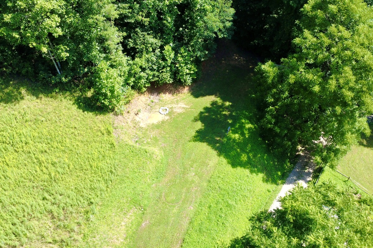 Grass RV site with fire ring, hookups, and extra tent space.