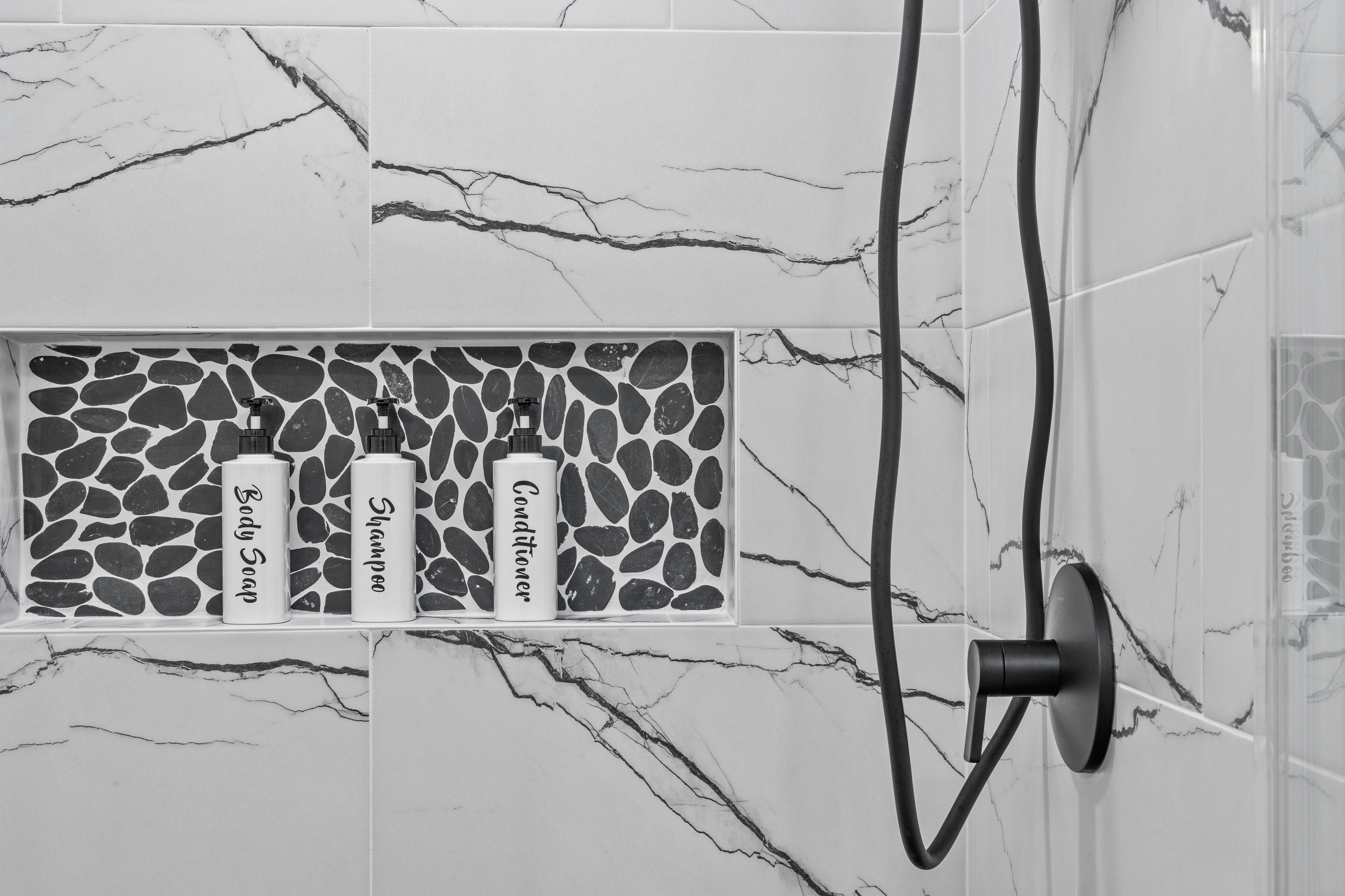Beautifully tiled walk-in shower stocked with complimentary amenities.