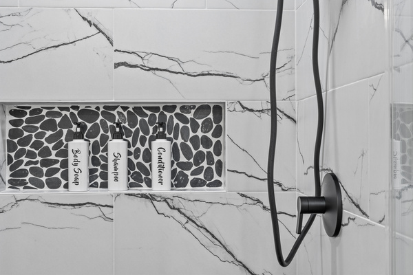Beautifully tiled walk-in shower stocked with complimentary amenities.