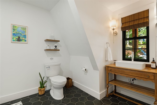 This 1st floor bathroom is located off the main living area. It features a full, tile-surround shower with rain showerhead and shower wand. The vintage desk was converted as a vanity for a touch of wimsy. Roman shades provide privacy & complete the space.