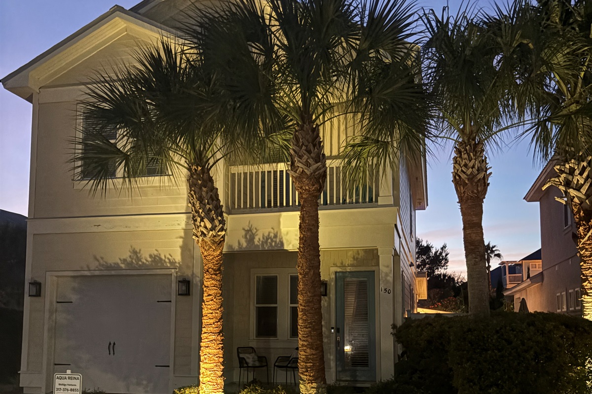 Evening exterior view highlighting the home’s coastal architecture and landscaping.