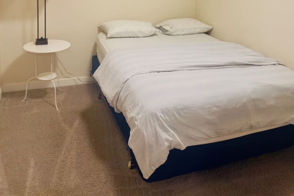 Cozy minimalist bedroom with queen bed, soft lighting, clean comfort.