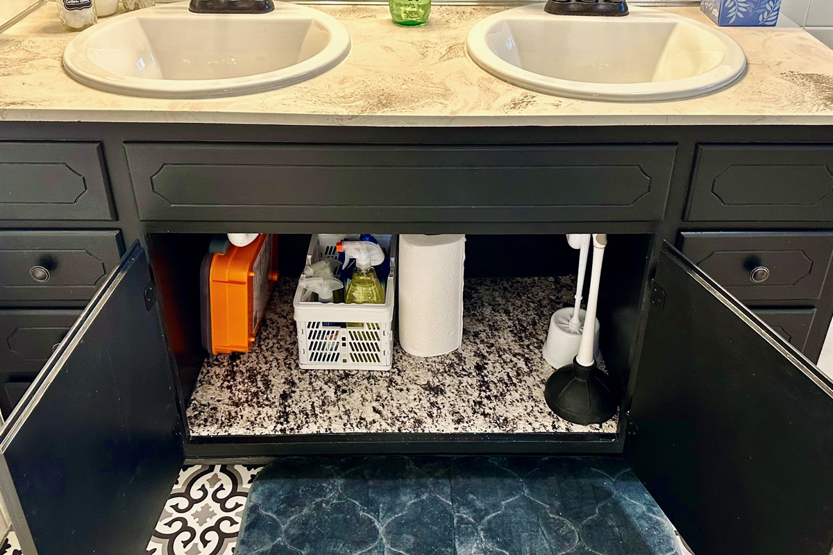 Main bathroom cabinet stocked with practical essentials, including a large first aid kit and bathroom-specific cleaning products. Everything is neatly organized and easy to find, giving guests peace of mind for both everyday needs and minor emergencies.