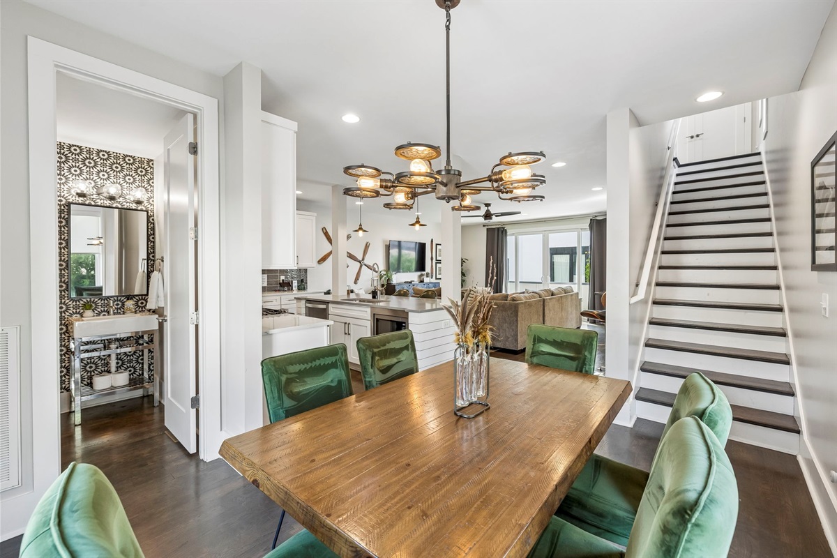 Light filled corner dining room with large windows and sleek contemporary layout - Olive green velvet chairs surround a warm wood table under a sculptural light fixture - Perfect for meals, board games, or casual coffee with natural sunlight all day