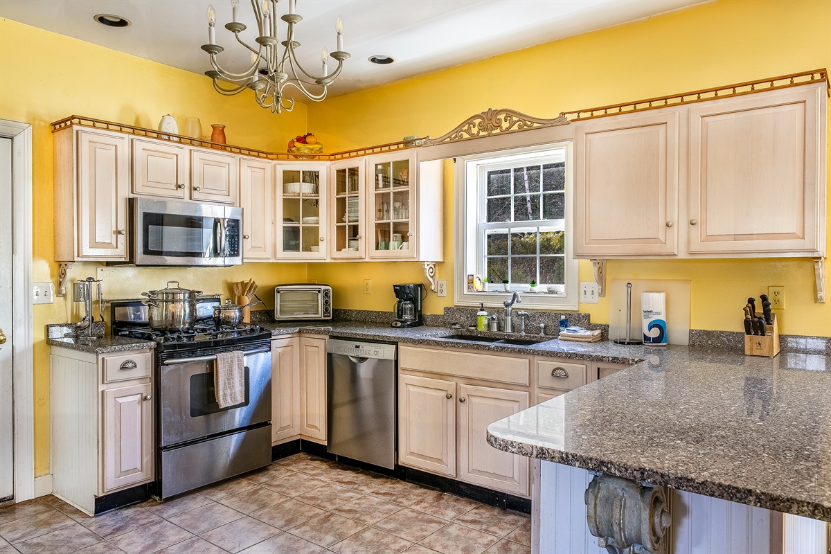 Prepare fresh local seafood in the fully equipped kitchen, featuring a KitchenAid gas range and oven. With ample stone counter space and a bright window view, this setup is perfect for everything from quick trail snacks to gourmet lobster dinners.