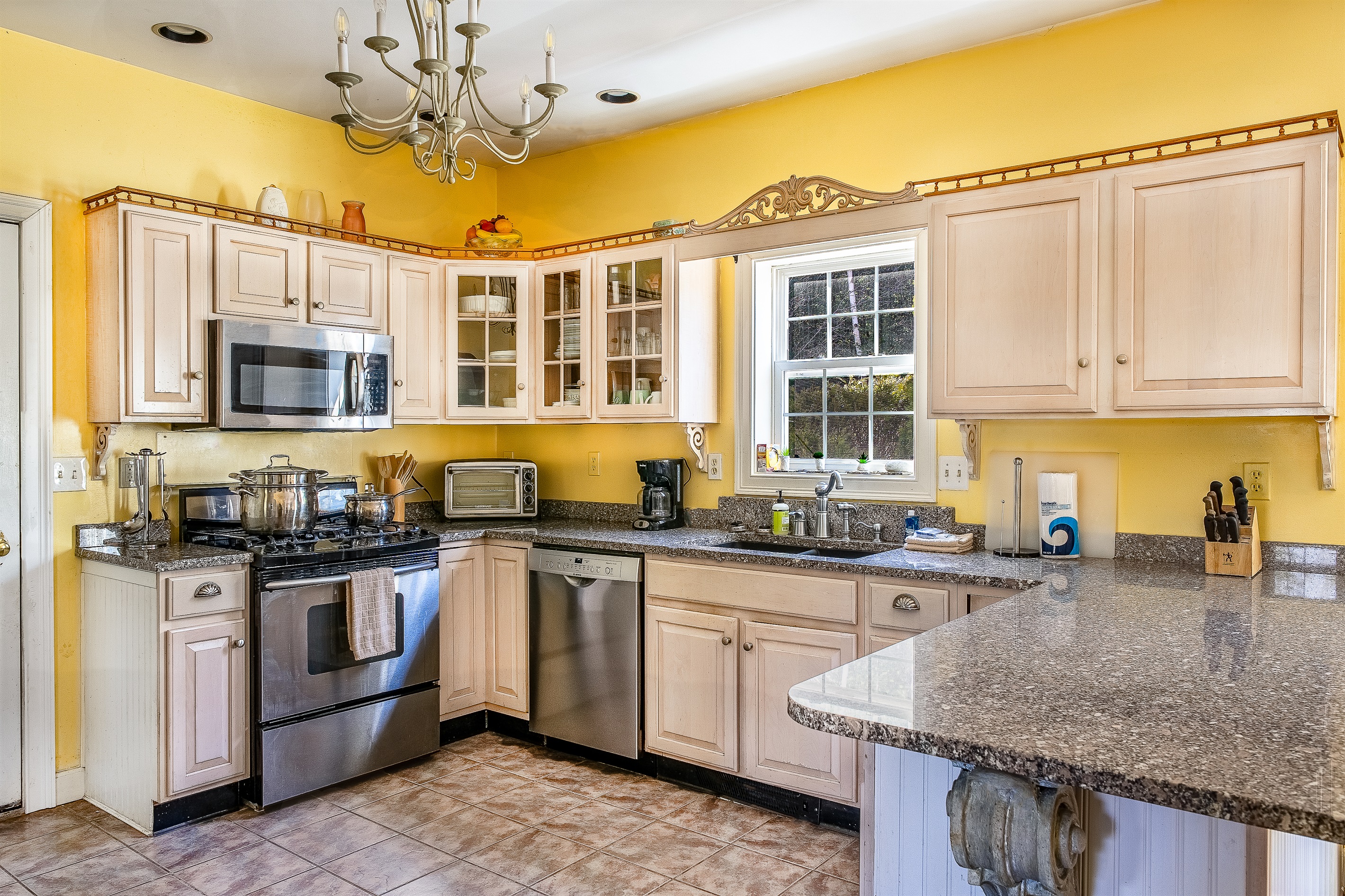 Prepare fresh local seafood in the fully equipped kitchen, featuring a KitchenAid gas range and oven. With ample stone counter space and a bright window view, this setup is perfect for everything from quick trail snacks to gourmet lobster dinners.