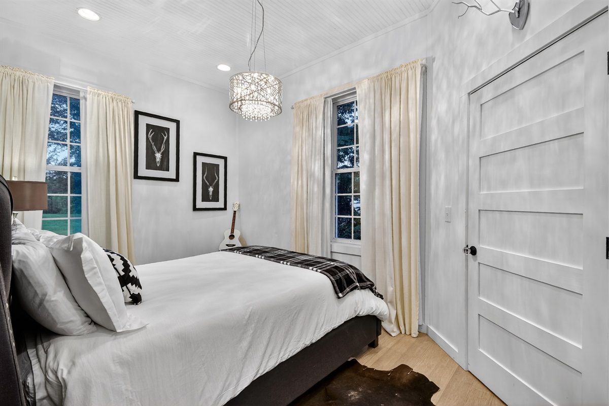 Wake up to soft morning light in this cozy queen bedroom, featuring warm textures, chic decor, and a peaceful view&mdash;perfect for couples or small families visiting Blue Ridge.