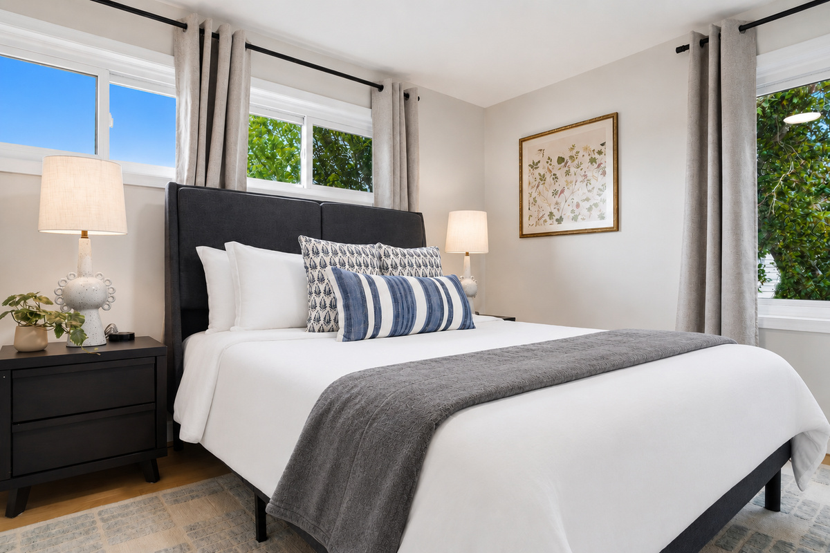 This serene bedroom features a comfortable bed, neutral decor, and large windows that fill the room with natural light, creating a calm and restful retreat.