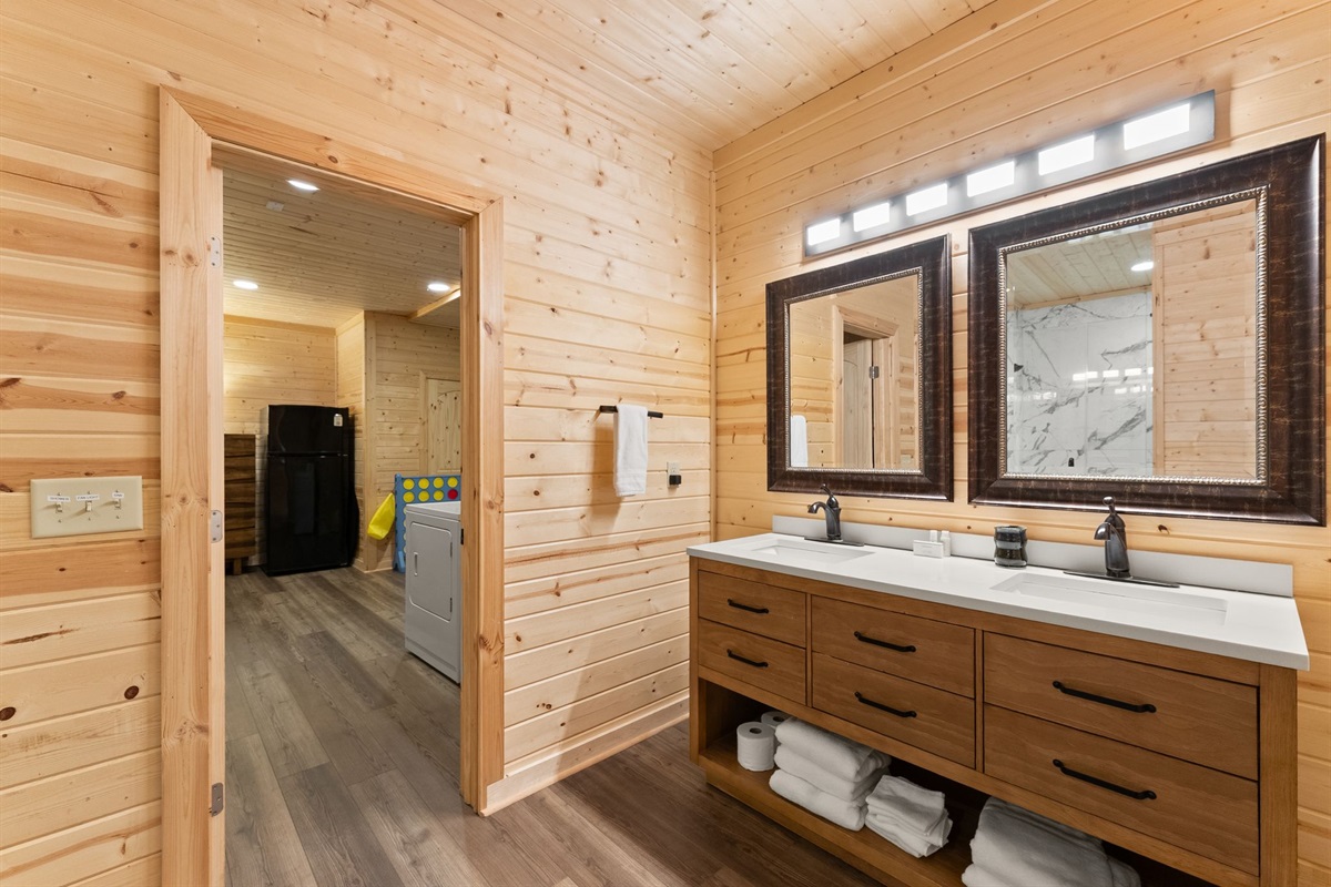 Lower-level full bathroom featuring dual vanity sinks, elegant mirrors, and a spa-like shower area for added comfort and convenience.