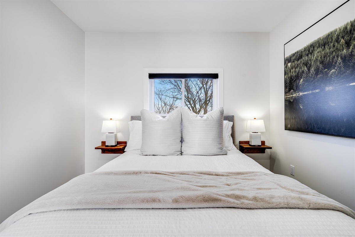 Queen bedroom with White walls that amplify natural textures.