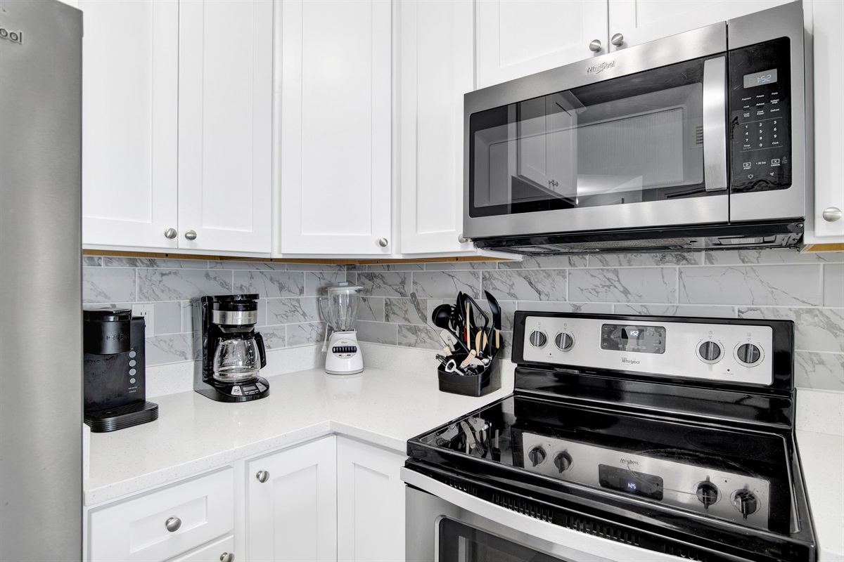 Kitchen with solid wood cabinets, quartz countertops, stainless steel appliances and a tiled backsplash