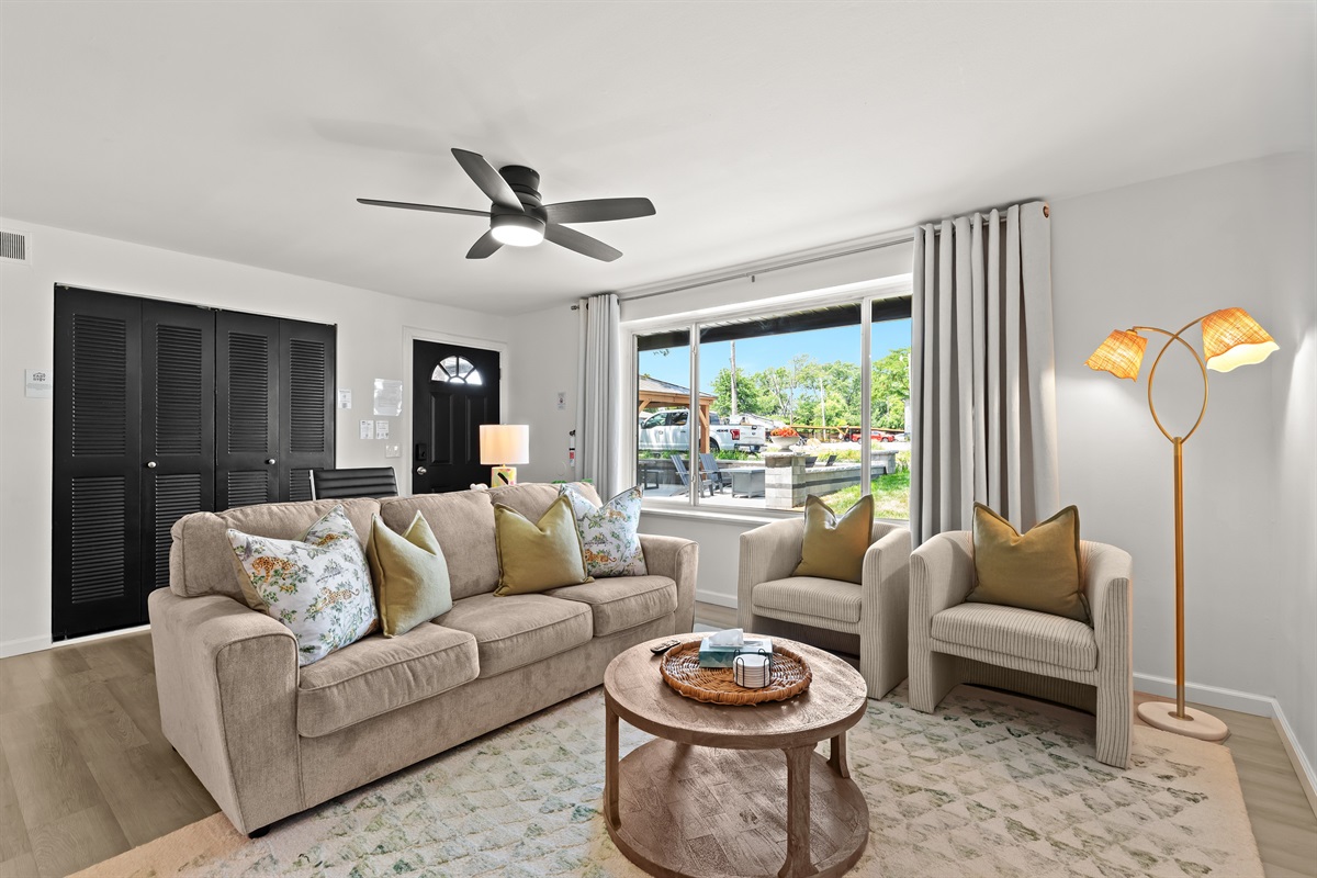 Bright and welcoming, this living area features a large window, comfy seating, and charming pillows for the perfect home-away-from-home vibe.