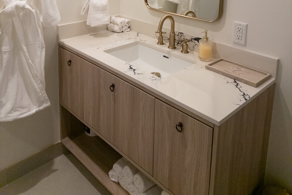 Spa-style bathroom - floating wood vanity, marble top and brushed-gold fixtures.